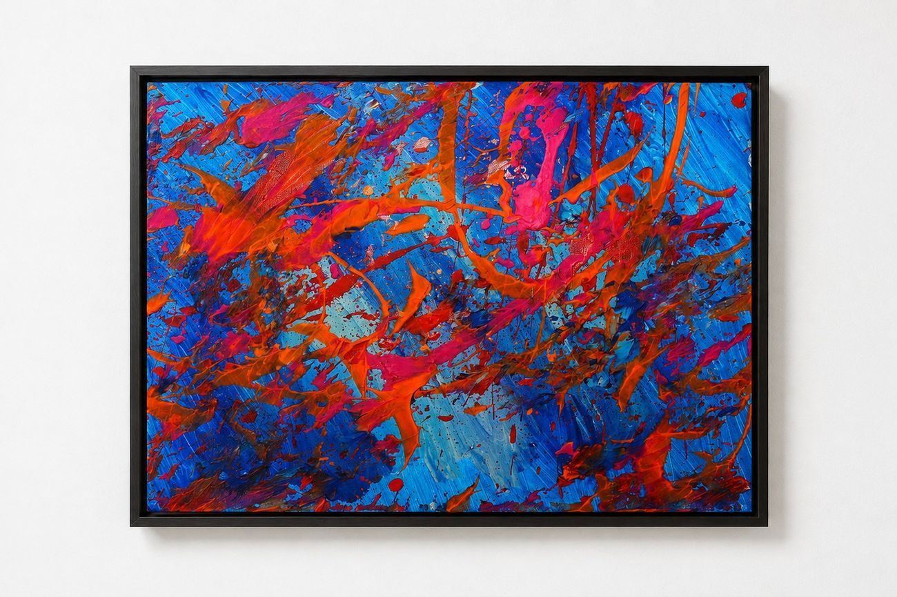 A blue canvas with orange and pink splatters, in a black frame